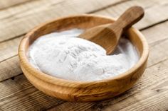 a wooden bowl filled with white powder next to a wooden spoon