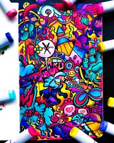 an art journal surrounded by crayons and colored pencils on a black background