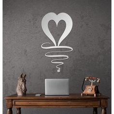 a laptop computer sitting on top of a wooden desk next to a wall mounted sculpture