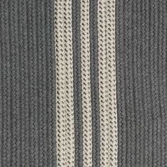 an area rug with two rows of braiding on it, in grey and white colors