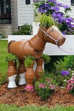 a horse shaped planter in the middle of a flower bed with purple flowers growing out of it