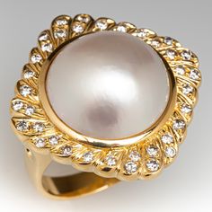 This fabulous vintage cocktail ring is centered with one (1), bezel set, round maybe' pearl and is bordered with thirty-six (36), bead set, round brilliant cut diamond. The ring measures 24.9mm at the top, rises 11.0mm above the finger, tapering to 3.4mm wide and 1.1mm thick at the base of the shank. The ring is currently size 6.5. Vintage Gold And Platinum Cocktail Rings, Luxury Antique Pearl Ring With Diamond, Luxury Classic Pearl Ring With Rose Cut Diamonds, Luxury Yellow Gold Brilliant Cut Pearl Ring, Luxury Antique Style Cabochon Pearl Ring, Elegant Dome Ring With Cabochon For Wedding, Formal Cabochon Pearl Ring, Classic Formal Pearl Ring With Cabochon, Classic Cabochon Pearl Ring For Formal Occasions