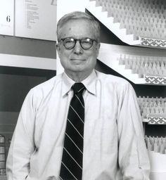 an older man wearing glasses and a tie standing in front of a wall with stairs