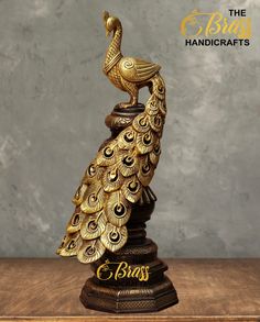 a golden peacock statue sitting on top of a wooden table