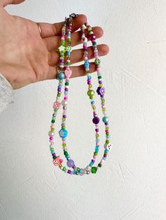 a hand holding a multicolored beaded necklace