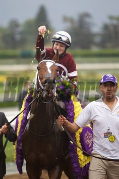 the jockeys are riding their horses down the track with one man on his horse