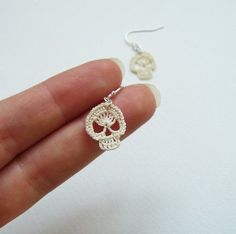 a hand holding a pair of silver earrings