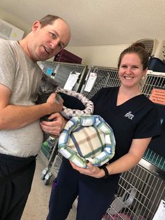 a man and woman standing next to each other in a pet store holding a cat