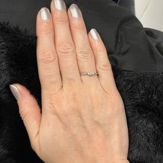 a woman's hand with white nail polish and a diamond ring on her finger