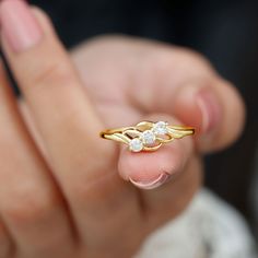 a close up of a person's hand holding a gold ring with two diamonds