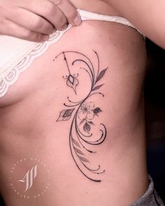 a woman's stomach with an artistic tattoo design on the side, and flowers