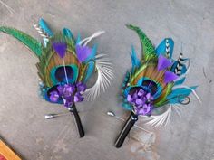 two peacock feathers with purple flowers on each side and black hair pins in the middle