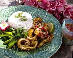 a green plate topped with meat and veggies next to rice