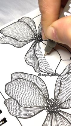 someone is drawing flowers on a piece of paper