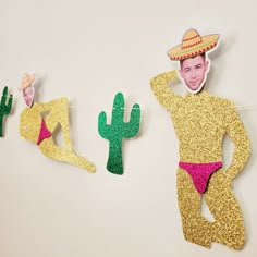 some paper cutouts are hanging on a wall with cactus decorations and a man in a sombrero