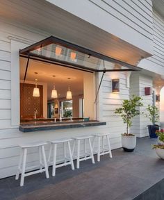 an outdoor bar with stools and potted plants on the side of a house