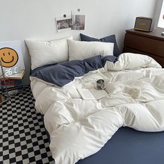 an unmade bed with pillows and blankets on it in a room that has black and white checkered flooring