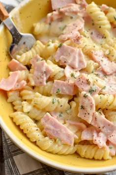 a yellow bowl filled with pasta and ham