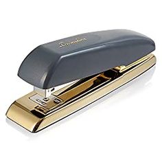 a stapler that is sitting on top of a white surface with gold trimming