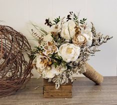 a bouquet of flowers sitting on top of a wooden block next to a wire wreath