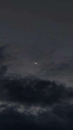 the moon is seen through some dark clouds