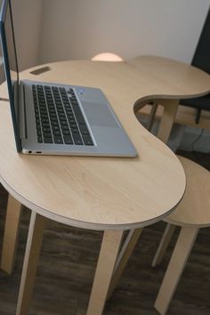 an open laptop computer sitting on top of a wooden table next to two small chairs