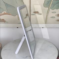 an electronic device sitting on top of a white table next to a wall with paintings