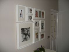 a wall with many pictures on it and a vase full of flowers in the corner