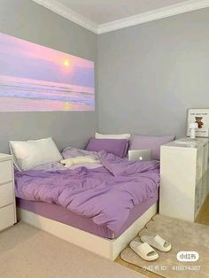 a bed with purple sheets and pillows in a bedroom next to a painting on the wall