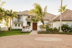 a large white house with palm trees and landscaping