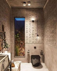 a bathroom with egyptian writing on the walls and a toilet in the middle, next to a window