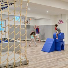 two children are playing in an indoor basketball court with ropes and balls on the floor