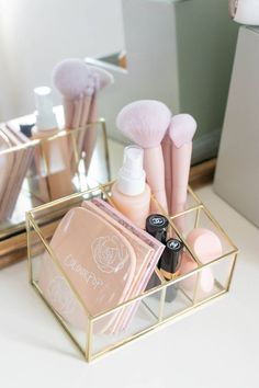 the makeup brush and other cosmetic products are in a gold holder on a white counter