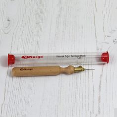 a pen with a wooden handle on top of a white wood table next to a screwdriver