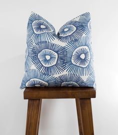 a blue and white pillow sitting on top of a wooden stool