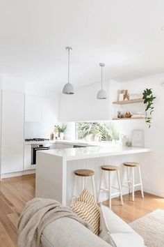 a white kitchen with an island and bar stools in the middle of the room