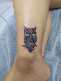 an owl tattoo on the foot of a woman's leg is shown in black ink