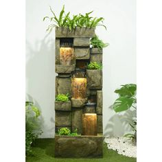 a tall planter filled with lots of plants next to a wall mounted water fountain