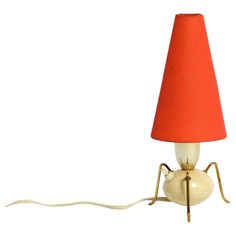 a lamp with a red shade on it and a white cord attached to the base