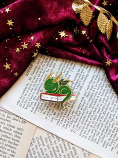 a brooch sitting on top of an open book next to a red velvet cloth