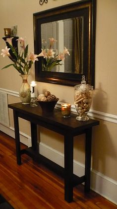 a table with vases and candles on it in front of a mirror, next to a lamp