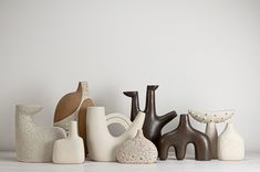 a group of ceramic vases sitting on top of a white table next to each other