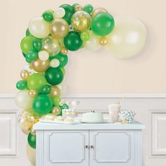 the balloon arch is decorated with green, white and gold balloons for an elegant tea party