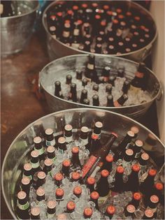 three buckets filled with bottles of beer sitting on top of a table