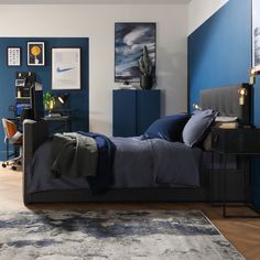 a bedroom with blue walls and artwork on the wall, including a black bed frame