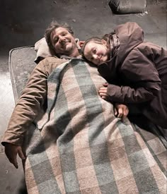 a man and woman laying down on a blanket