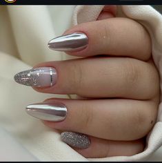 a woman's hand with some silver and white nail polishes on her nails