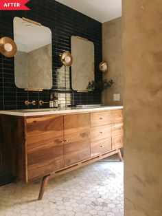 a bathroom vanity with two mirrors above it and a tiled wall in the back ground