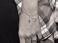 a woman's hand with a small tattoo on the left wrist and a crescent