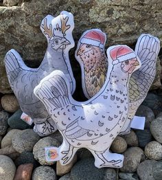 two ceramic chickens with santa hats on their heads are standing in front of some rocks